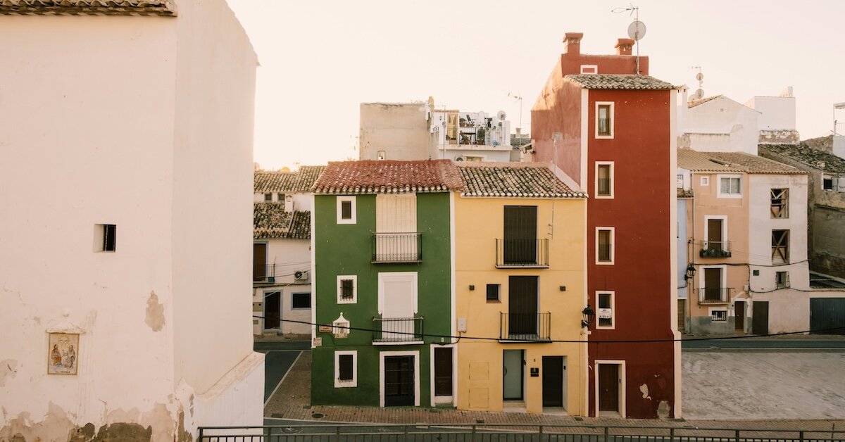 Colorful older apartment buildings sit on the corner of an old street