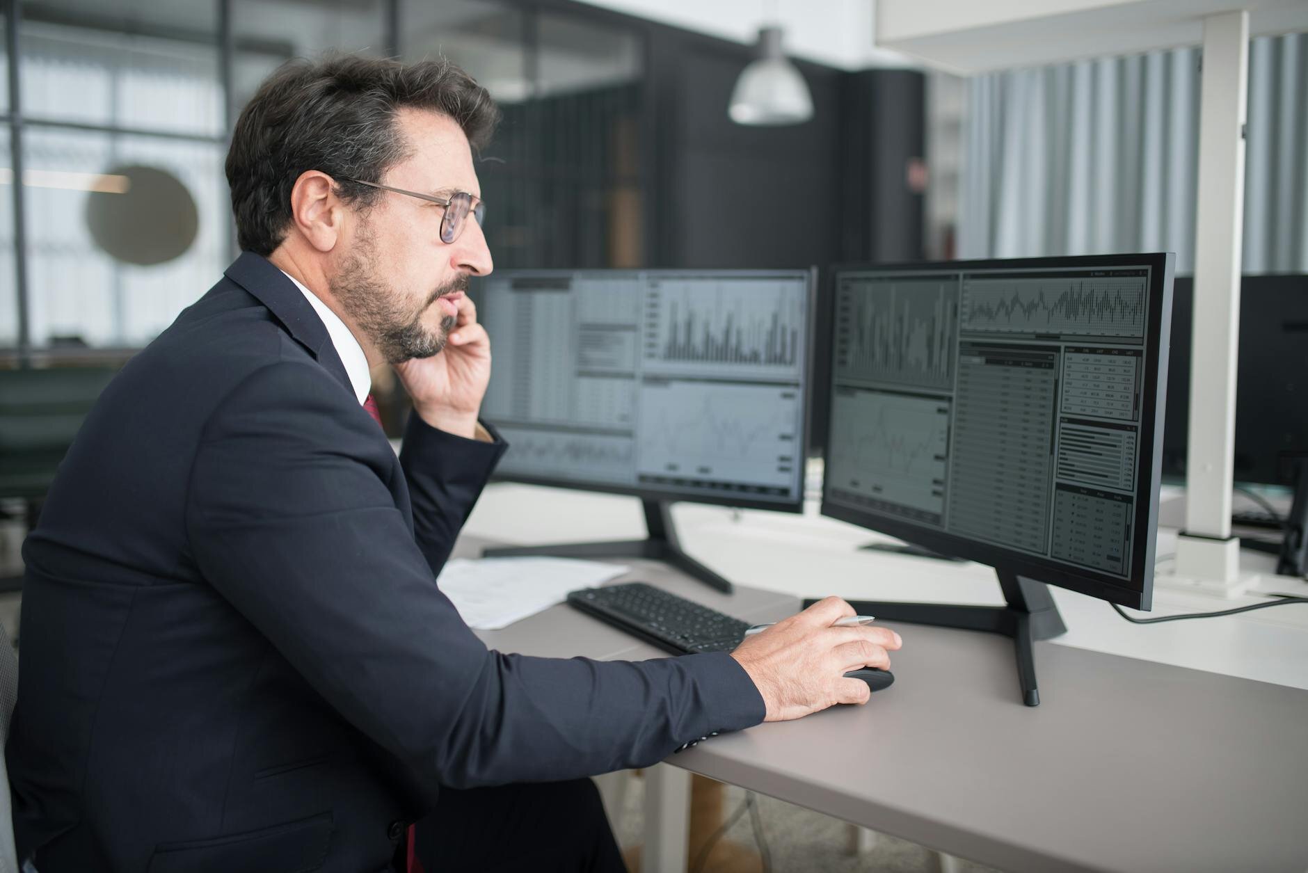 man on the phone looking at two computers