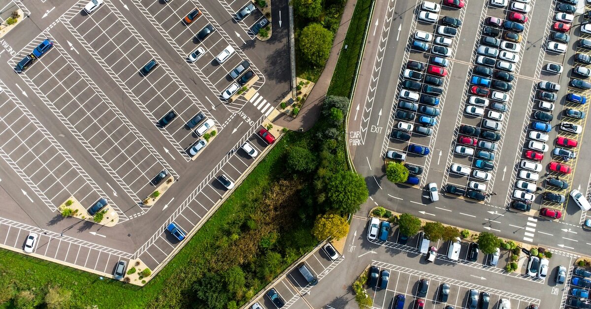 A drone photo of a full parking lot and an empty parking lot to the left