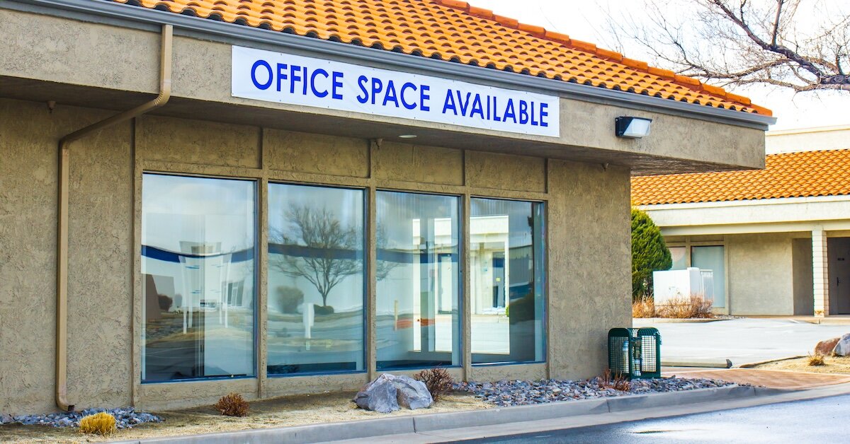 A brown building with large glass windows and a sign reading "Office space available"