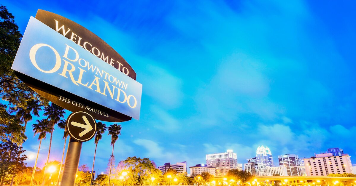 A sign that says "Welcome to Downtown Orlando" with the city in the background