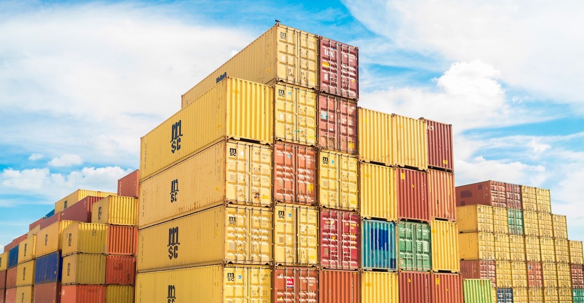A stack of industrial shipping containers stand piled in various colors.