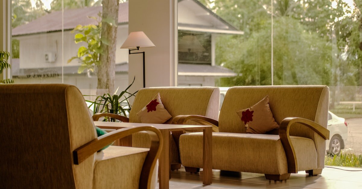 Green sofa chairs in a waiting area with floor-to-ceiling windows.
