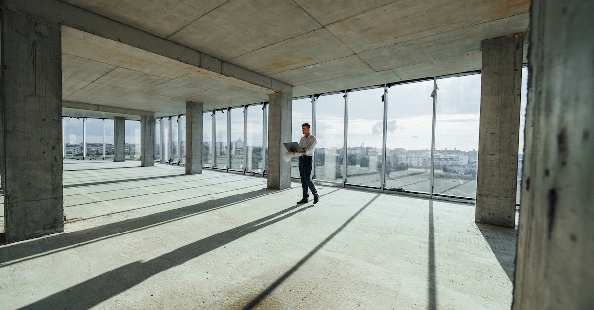 A person working on his laptop standing in a high floor in the middle of the office building