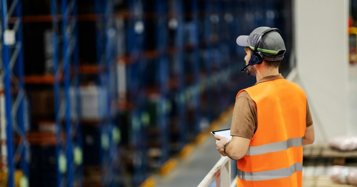 A construction worker checking off list items on an ipad in a warehouse