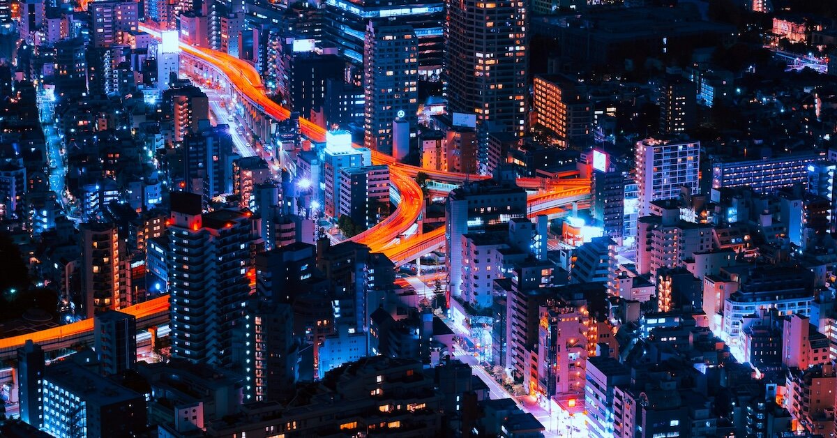 A futuristic cityscape at night with bright lights from buildings and highways