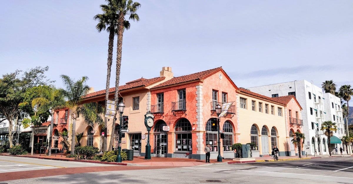 A colorful orange, yellow, and peach building alongside palm trees.