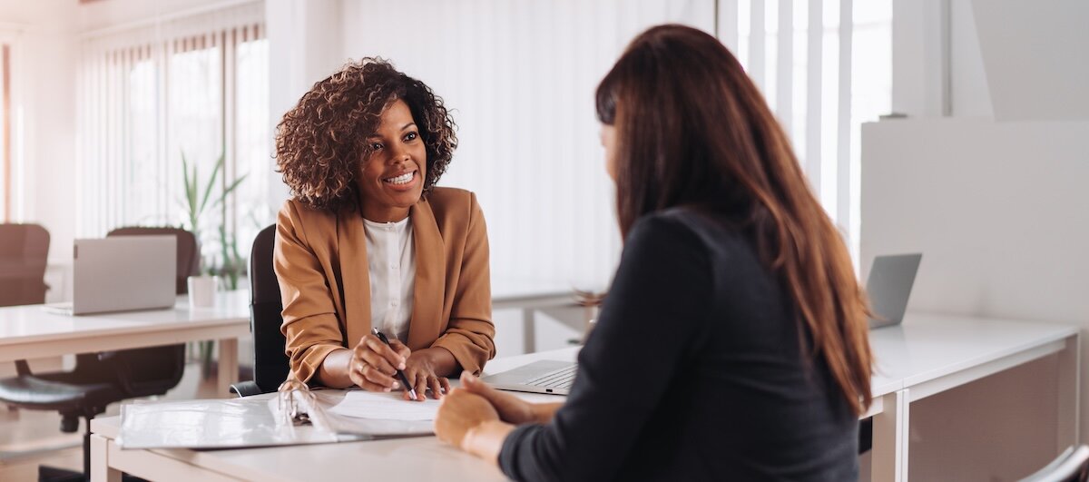 A businesswoman reviews documents with another person sitting across the table