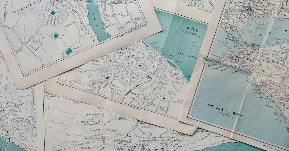 A pile of paper maps layered on top of a desk