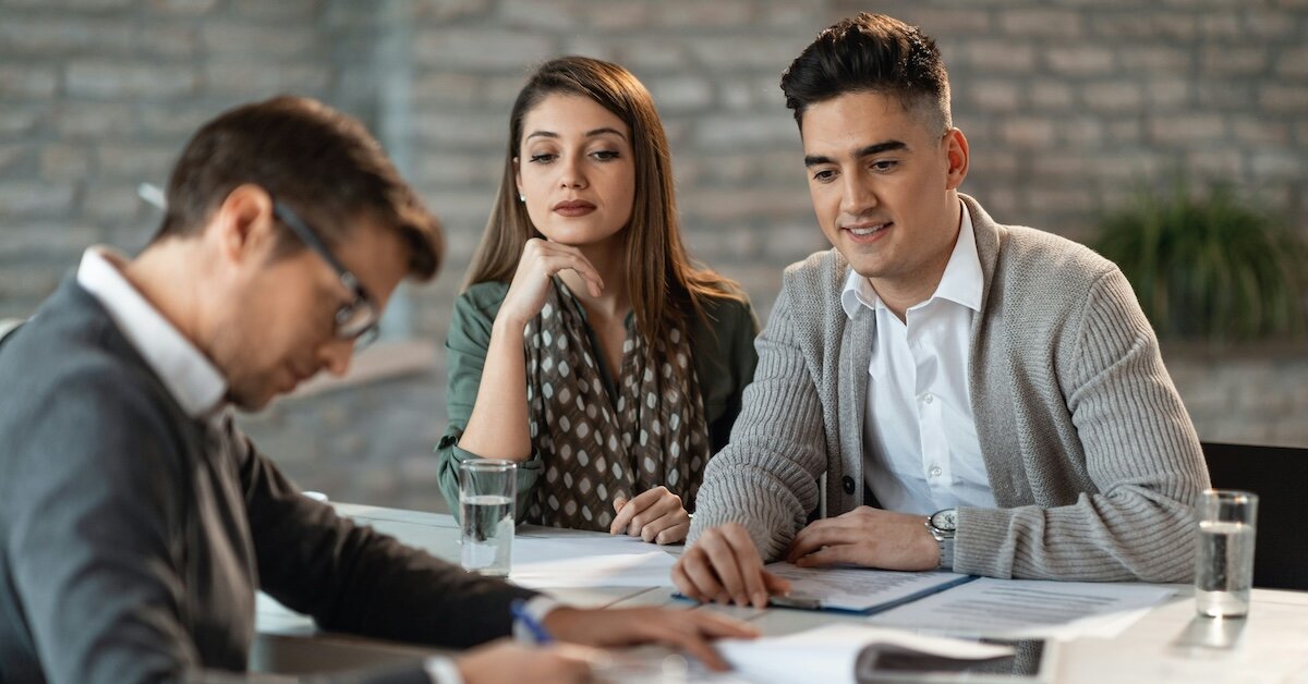 Business professionals review loan documents at a shared work table