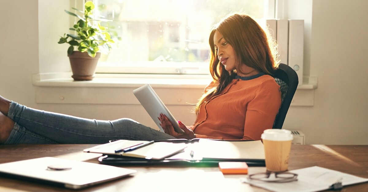 A woman reading an engaging email on her ipad at her desk