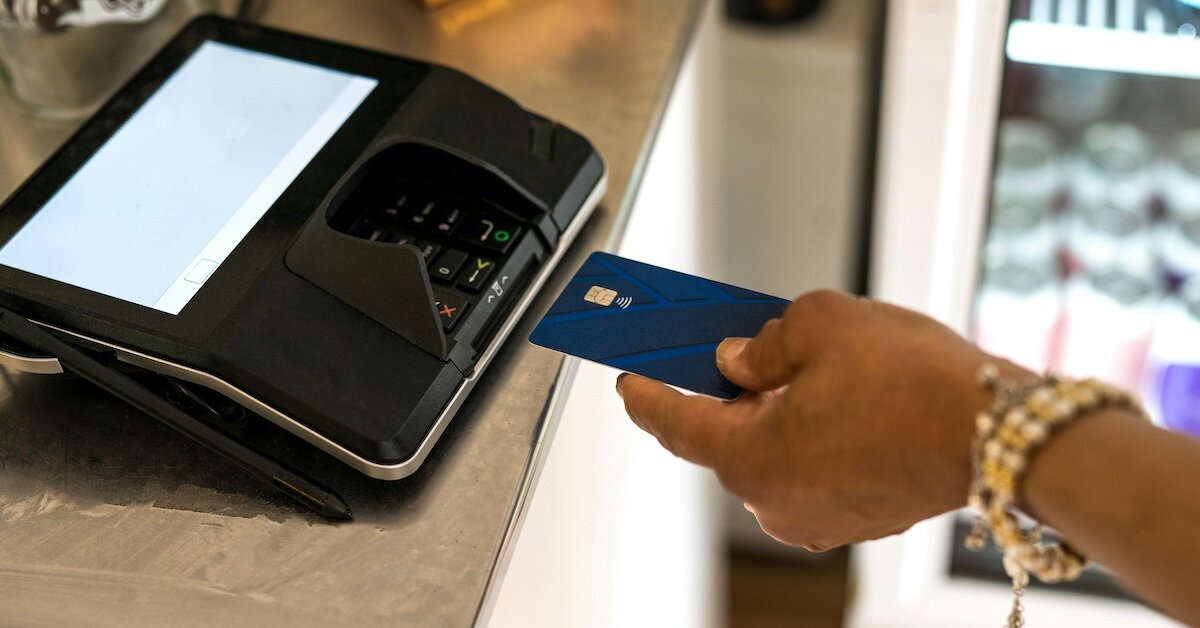 A woman is placing her credit card in a chip card reader machine