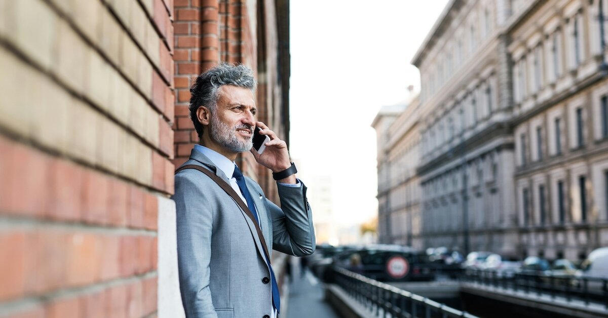 A man on a phone call discussing business negotiations outside on a city street