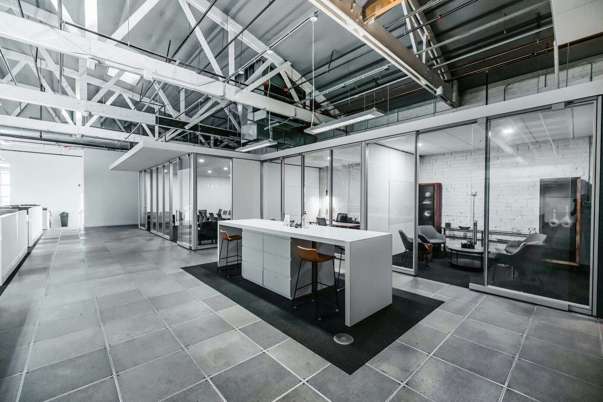 A gray-colored office central space with fishbowl conferences in the background