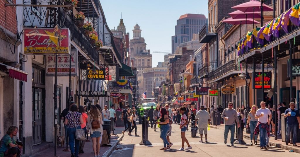 Pedestrians walk down a street lined with shops in downtown New Orleans