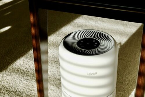 A Levoit air purifier placed under a table