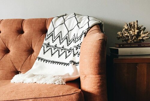 A brown sofa with a white throw blanket over the side
