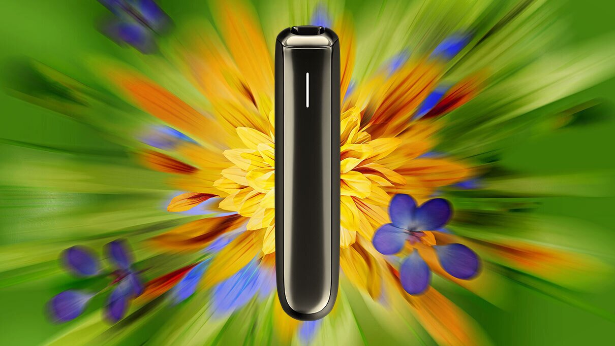 Ploom AURA Black uređaj na cvjetnoj pozadini u jarkim bojama