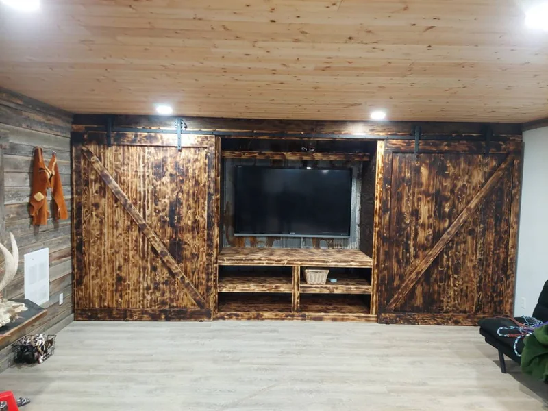 Custom stained wood barn doors installed around a television wall