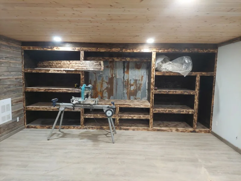Custom stained wood shelving and media cabinet being installed