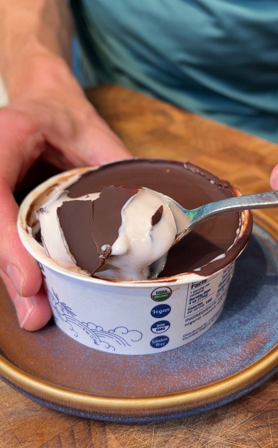 Protein Yogurt Cup with a spoon breaking top layer of chocolate
