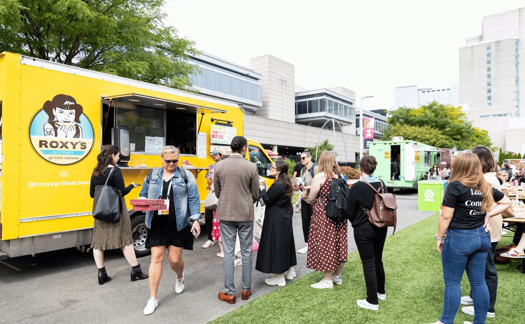 People lined up at a purple Moyzilla Boston food truck with cartoon mascot graphic and serving window open