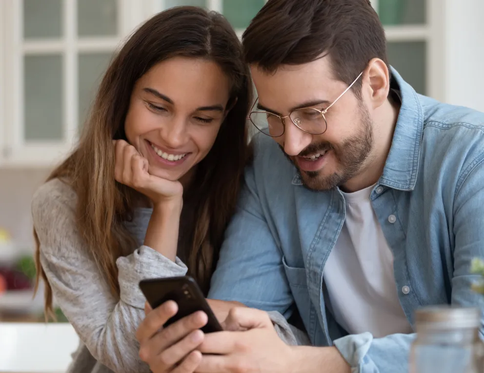 happy woman and man looking down at phone 
