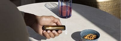 Hand holding Ploom AURA near coffee table-4