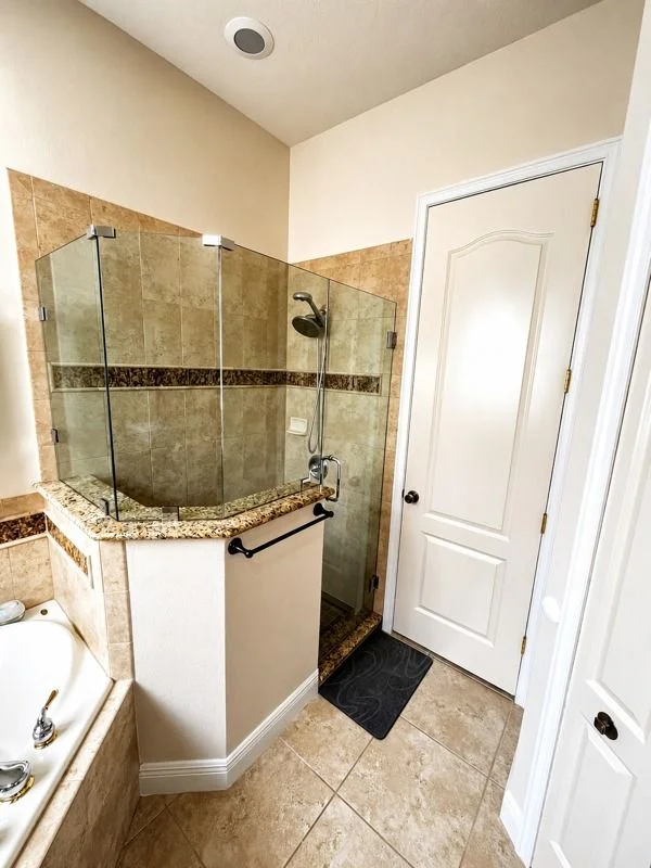 Frameless glass shower enclosure with warm stone tile
