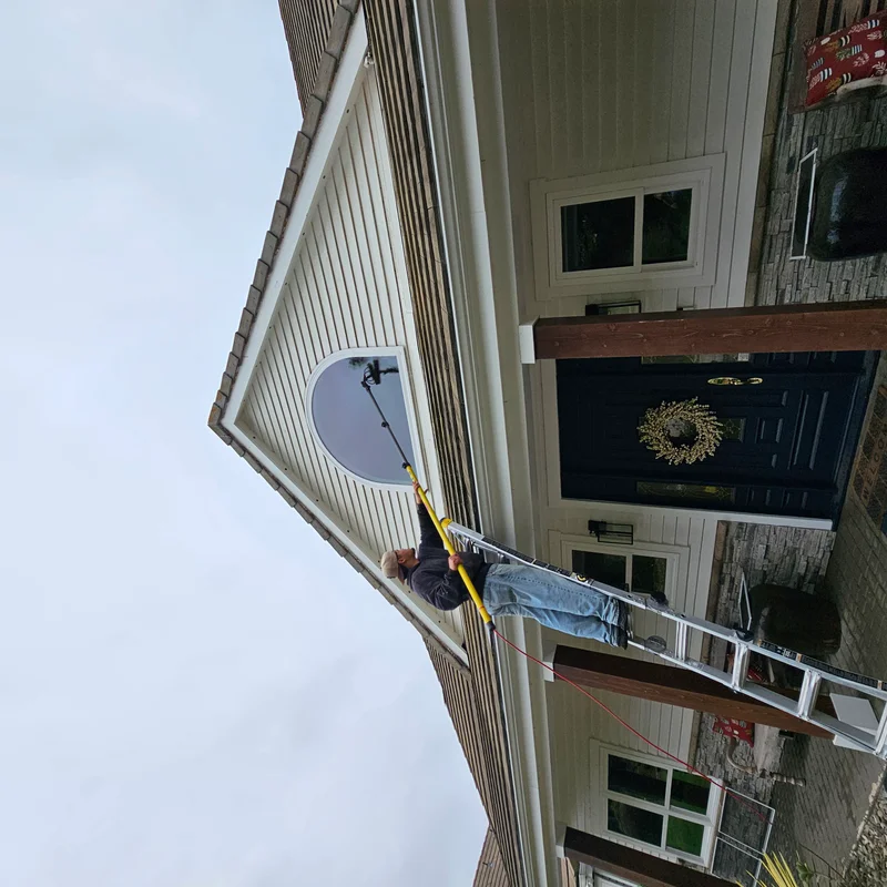 Technician cleaning a home exterior with professional equipment