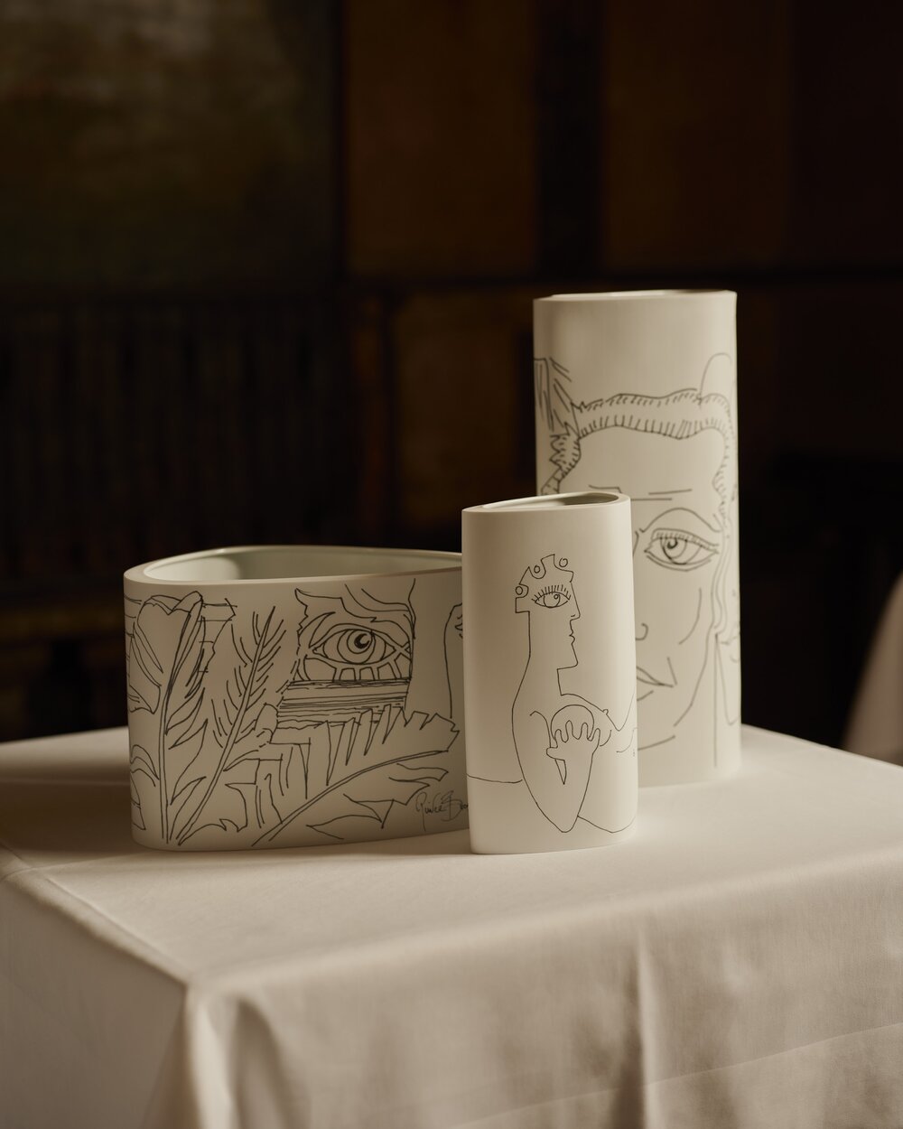 3 Vases bisque porcelain with drawings from Pierce Brosnan on table and black background