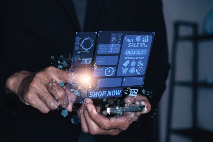 A hand holding an holographic display of purchasing and sales icons. 