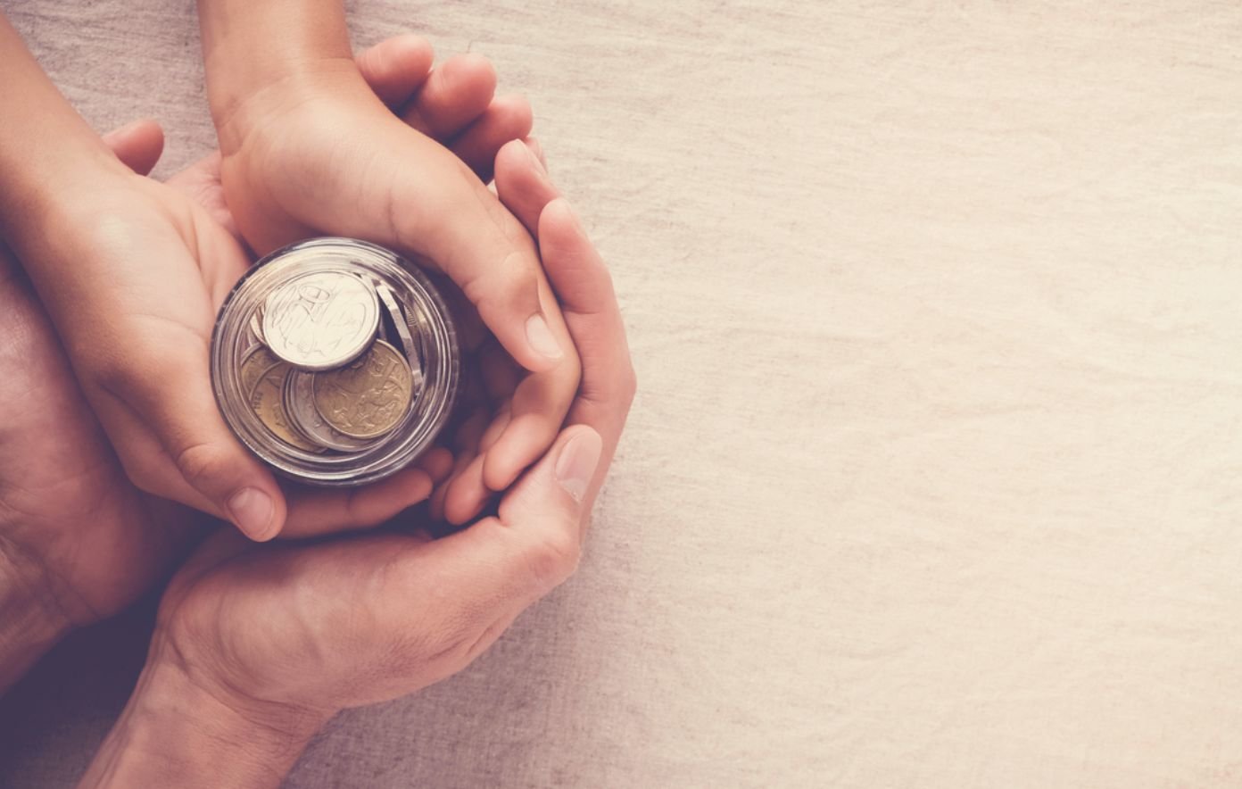 A child and an adult hold a coin jar