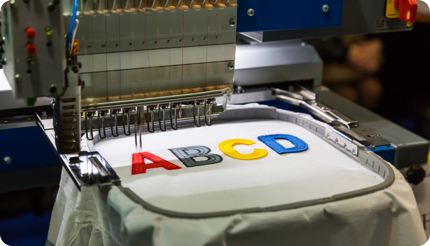 Close-up of an embroidery machine stitching colorful letters 
