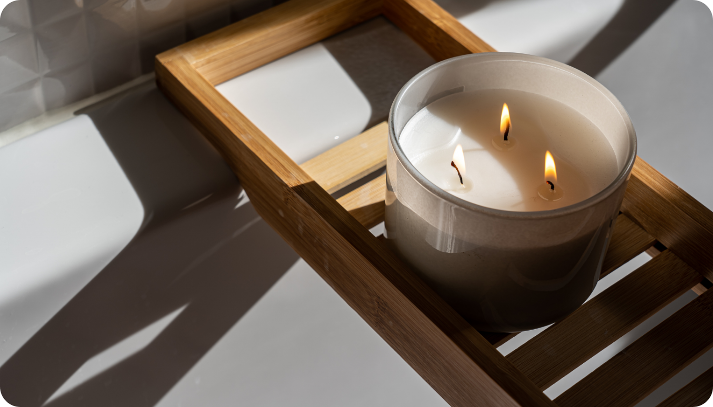 Three-wick candle burning on top of a wooden bath caddy