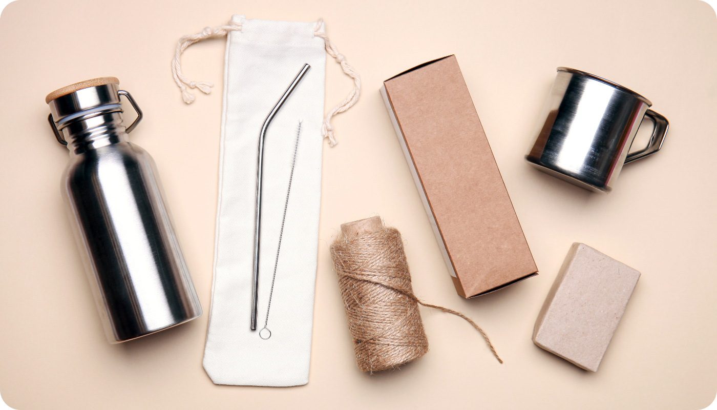Examples of sustainable swag, including stainless steel water bottle, reusable straw, stainless steep mug, soap, and sustainable packaging materials