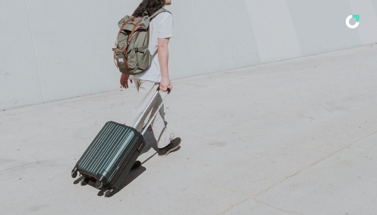 Person with a backpack is pulling a suitcase, preparing for travel