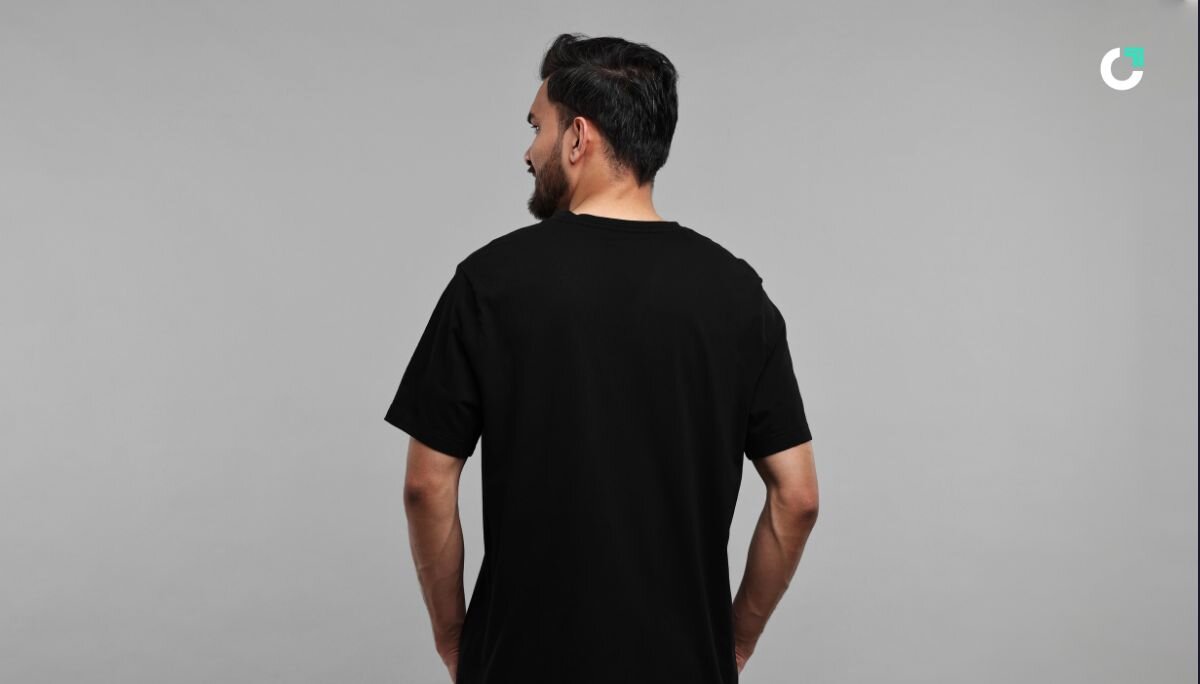 Back view of a man wearing a plain black t-shirt against a gray background, showcasing the fit and cut of the shirt without any visible branding or design.