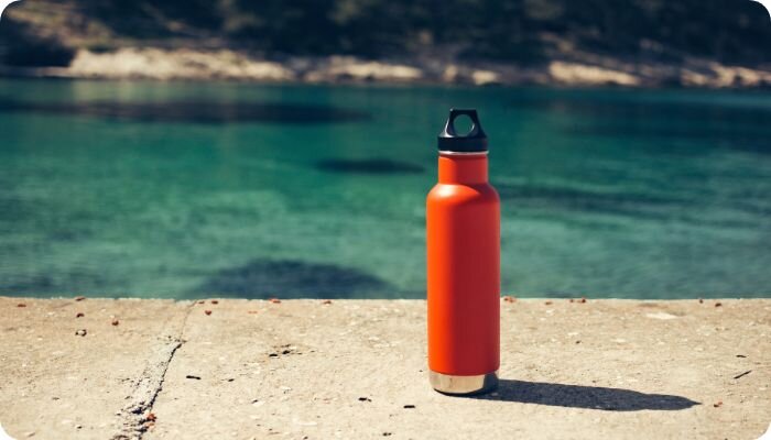 Bright red water bottle by a swimming pool