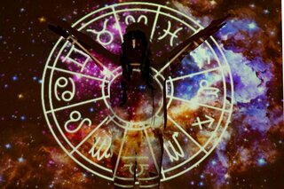 a figure dancing in front of a projected image of zodiac signs