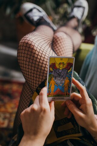 someone holding the lovers tarot card on their lap