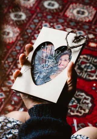 a hand holding a broken heart shaped picture frame