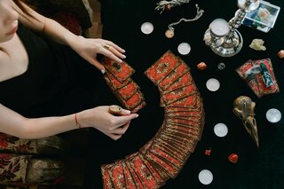 hands spreading tarot cards on a table