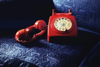 red rotary telephone on blue cushion
