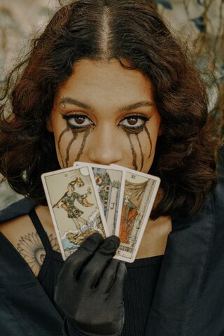 tear-streaked face with three tarot cards over their mouth