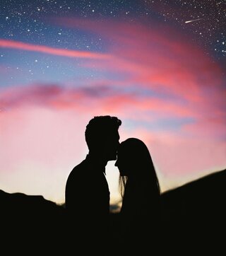 two people standing in silhouette in front of a sunset