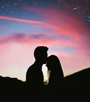 two people standing in silhouette in front of a sunset