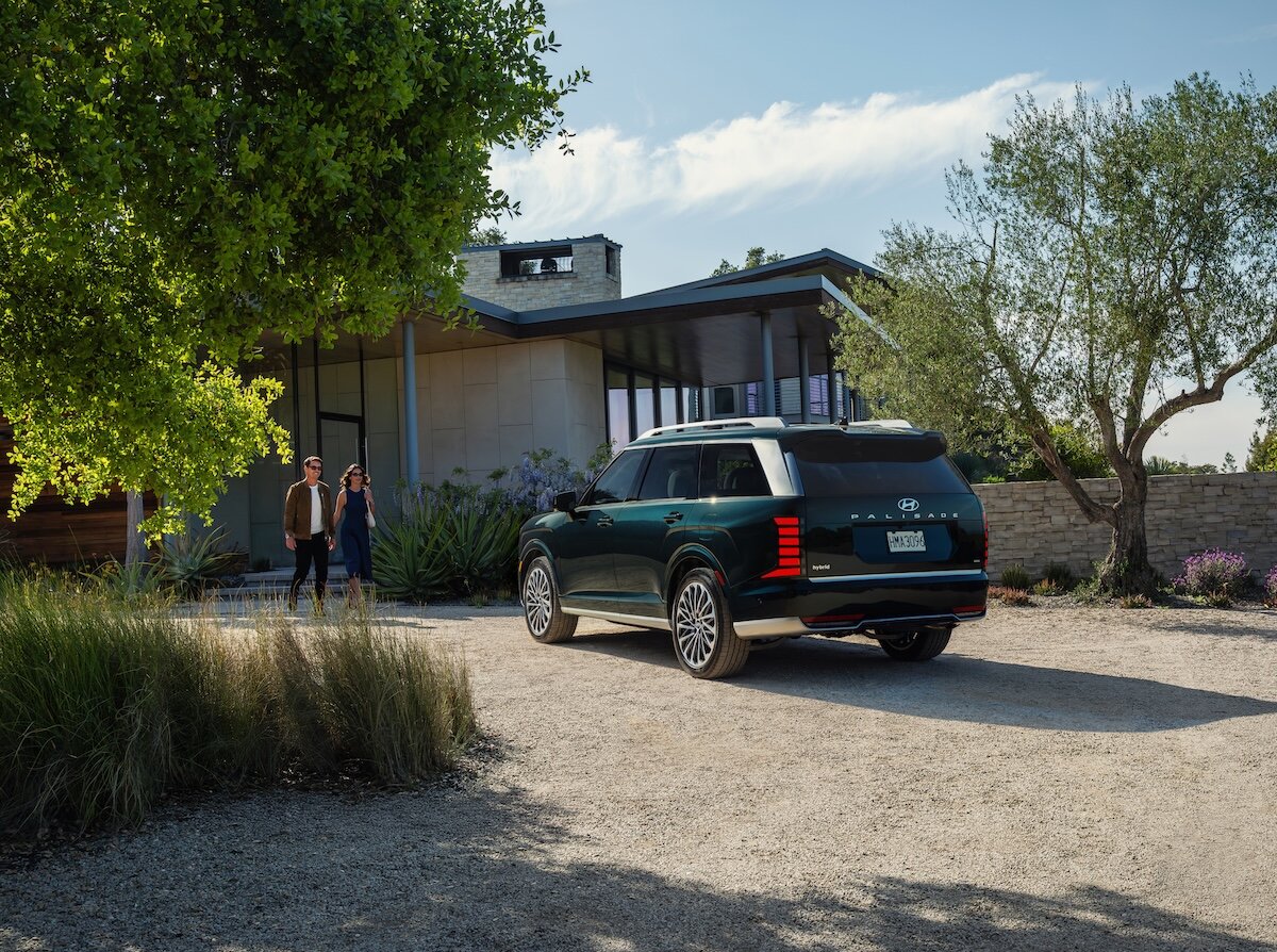 2026 Hyundai Palisade parked outside house, green rear three-quarter view, couple walking to car