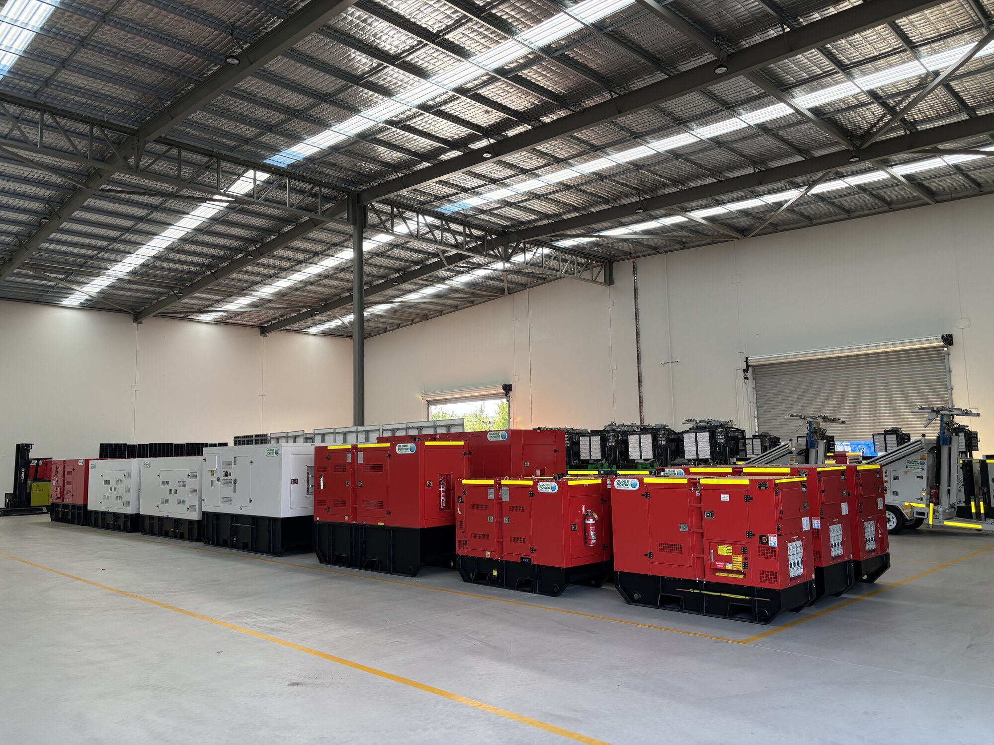 Rows of Globe Power generators stored and prepared for deployment in a modern equipment warehouse.