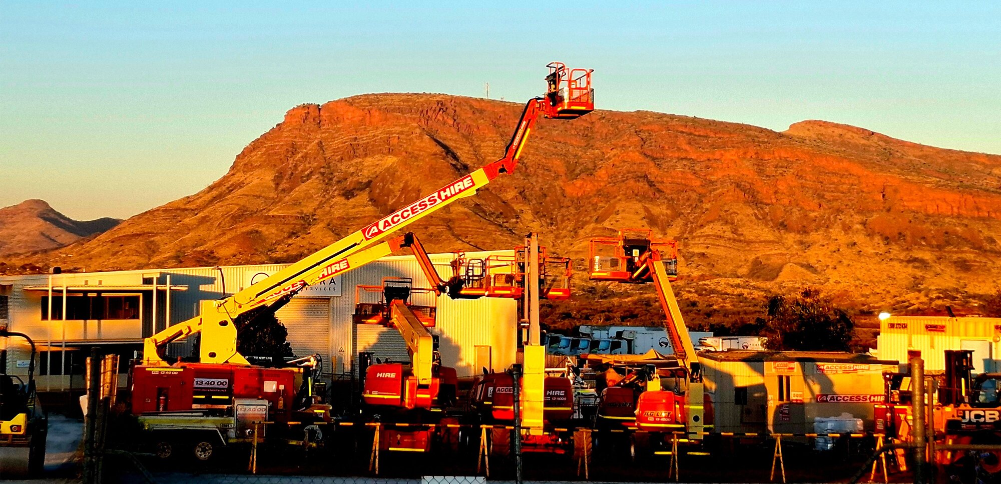 Access Hire Tom Price branch with boom lifts and access equipment against the Pilbara landscape.